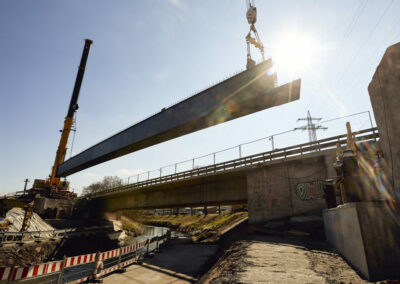 Der Stahlträger einer Autobahnbrücke wird von zwei Kränen eingesetzt